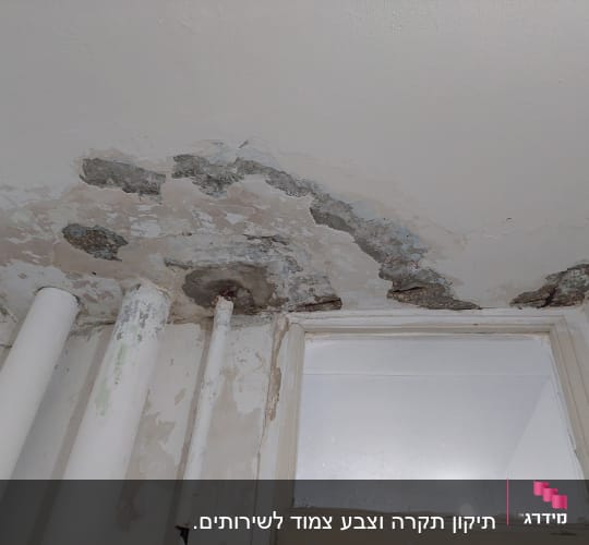 תקרה מתקלפת עם סימני רטיבות וצינורות חשופים